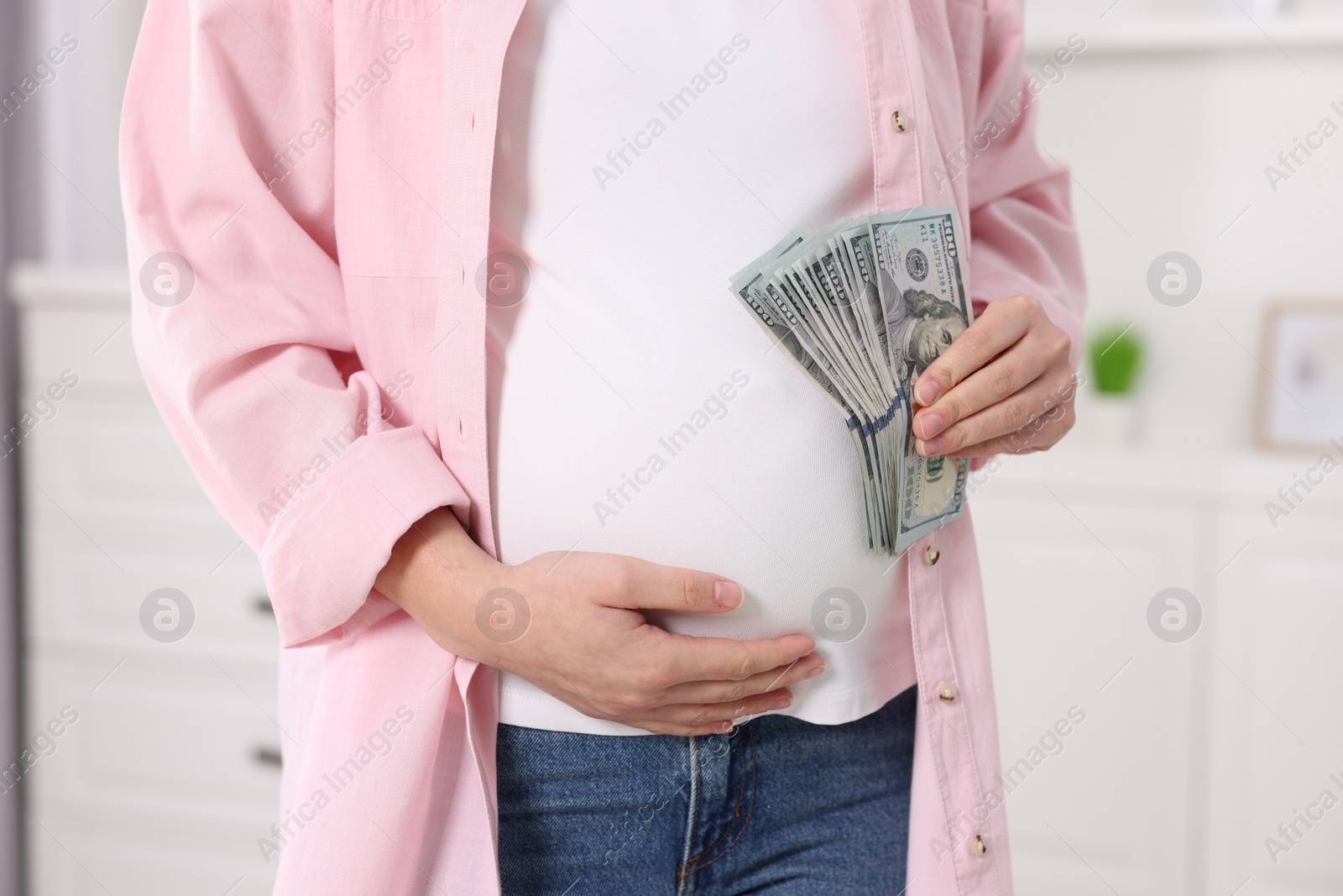 Photo of Surrogate mother. Pregnant woman with dollar banknotes indoors, closeup