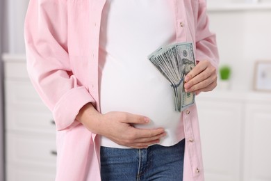 Surrogate mother. Pregnant woman with dollar banknotes indoors, closeup