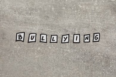 Photo of Word Bullying of paper pieces on light stone surface, flat lay