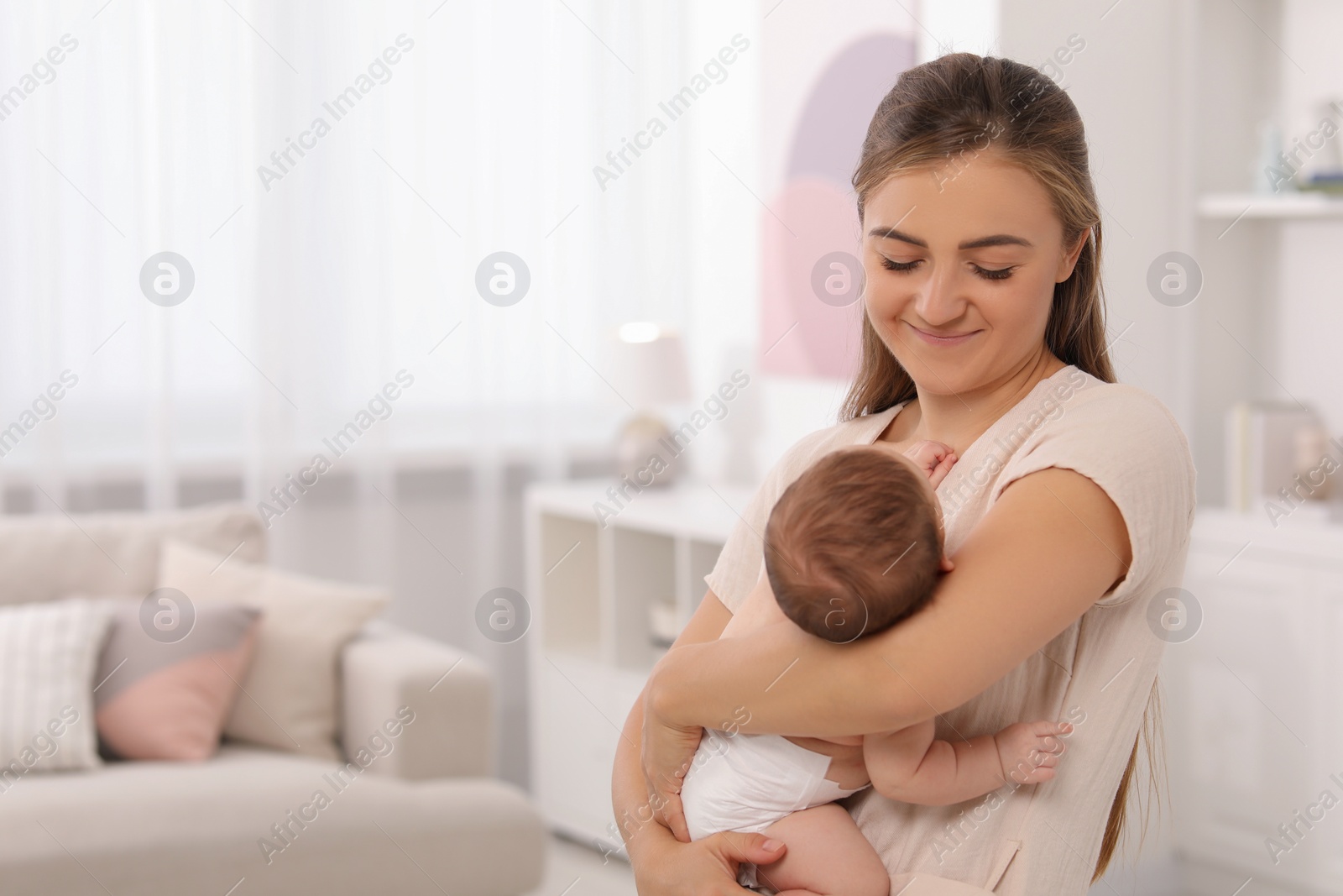 Photo of Mother holding her cute newborn baby in child's room, space for text