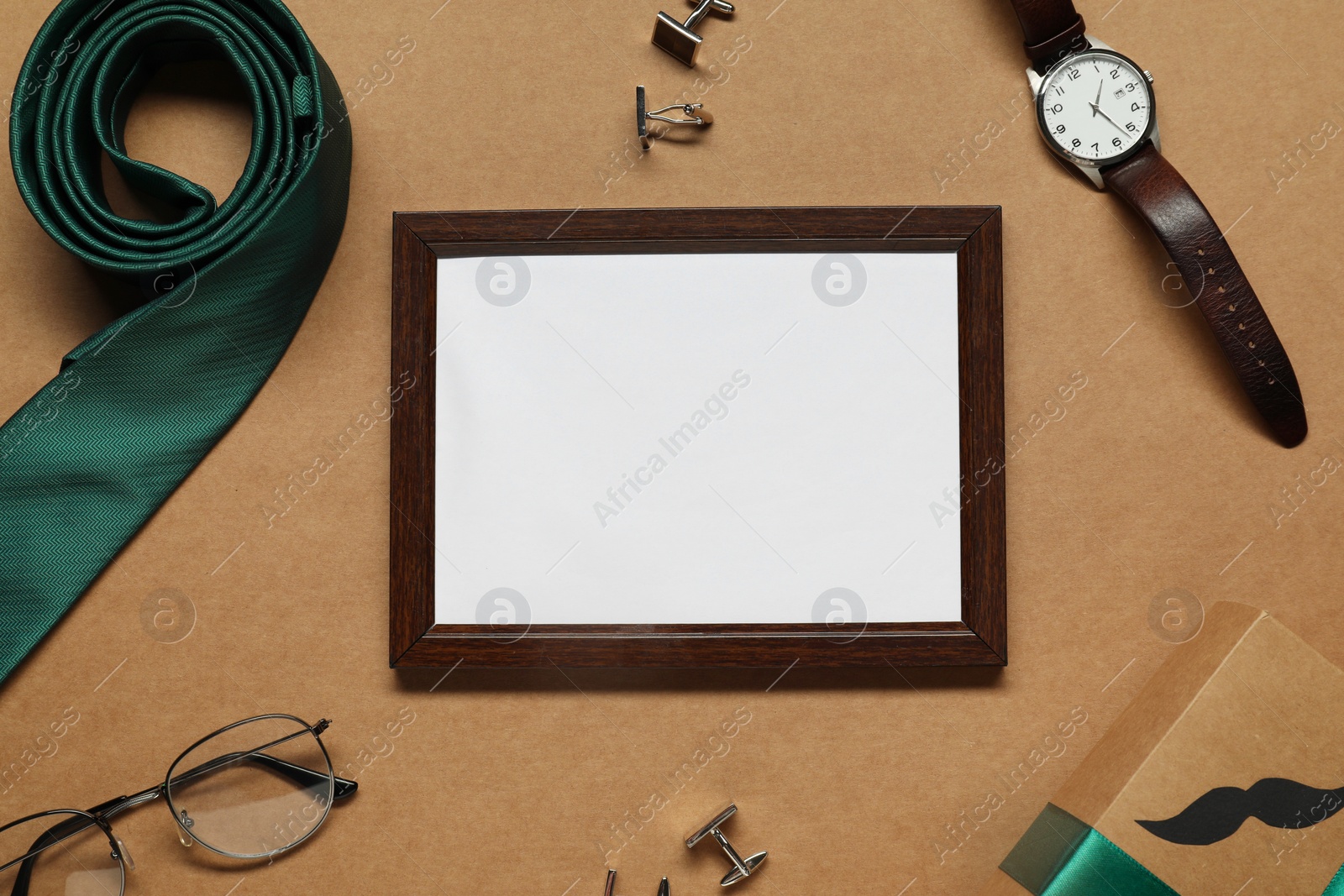 Photo of Empty photo frame, gift box and men accessories on brown background, flat lay with space for text. Father's day celebration