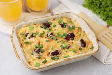 Photo of Tasty sausage casserole with green onions in baking dish on white table, closeup