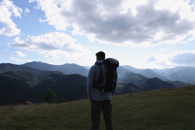 Photo of Tourist with backpack enjoying majestic mountain landscape, back view