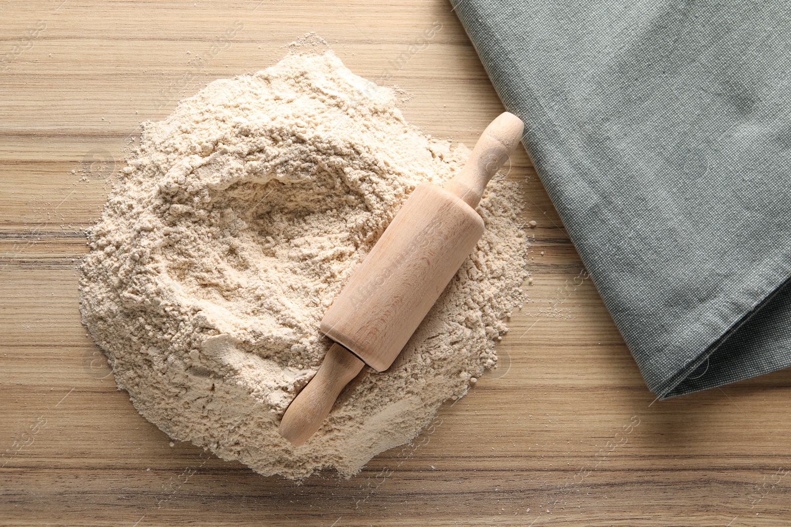 Photo of Pile of flour and rolling pin on wooden table, top view