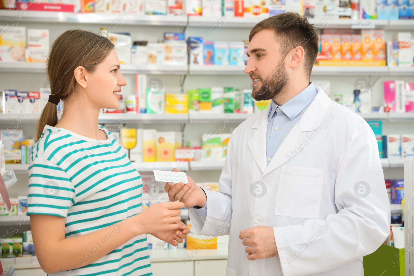 Photo of Professional pharmacist giving pills to customer in modern drugstore