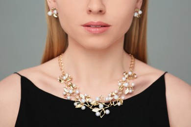 Photo of Woman with elegant jewelry on gray background, closeup