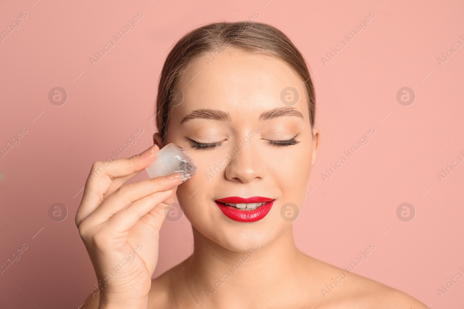 Photo of Young woman with ice cube on color background. Skin care