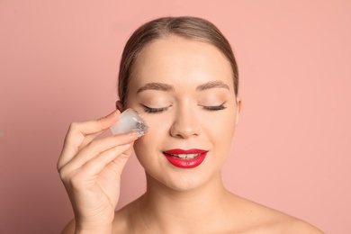 Young woman with ice cube on color background. Skin care