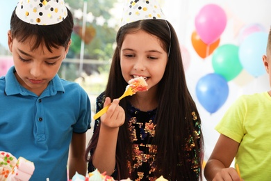 Happy children eating delicious cake at birthday party indoors