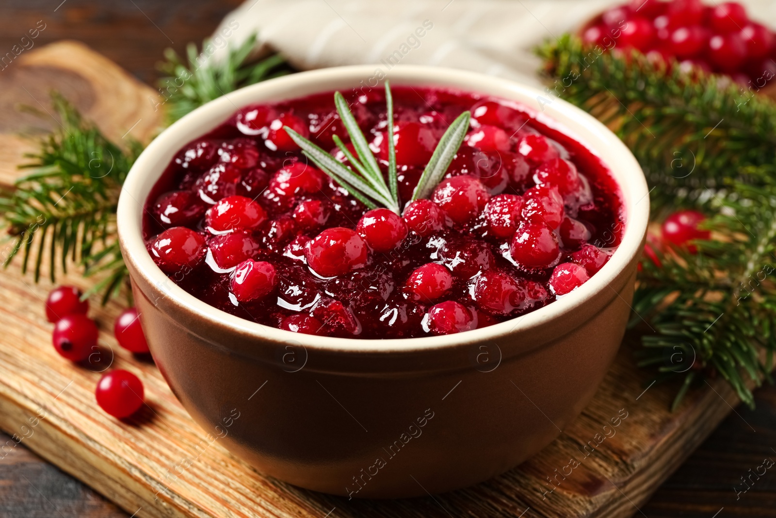 Photo of Fresh cranberry sauce with rosemary on wooden board, closeup