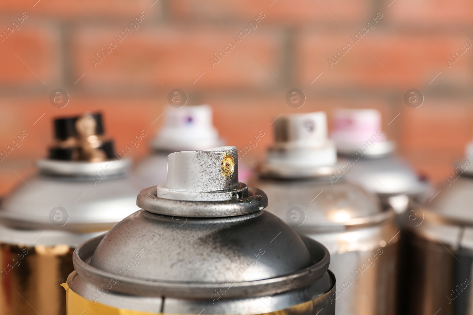 Photo of Used cans of spray paint on blurred background, closeup view