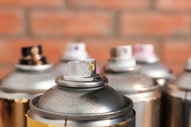 Photo of Used cans of spray paint on blurred background, closeup view