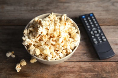 Bowl of popcorn and TV remote on wooden background. Watching cinema