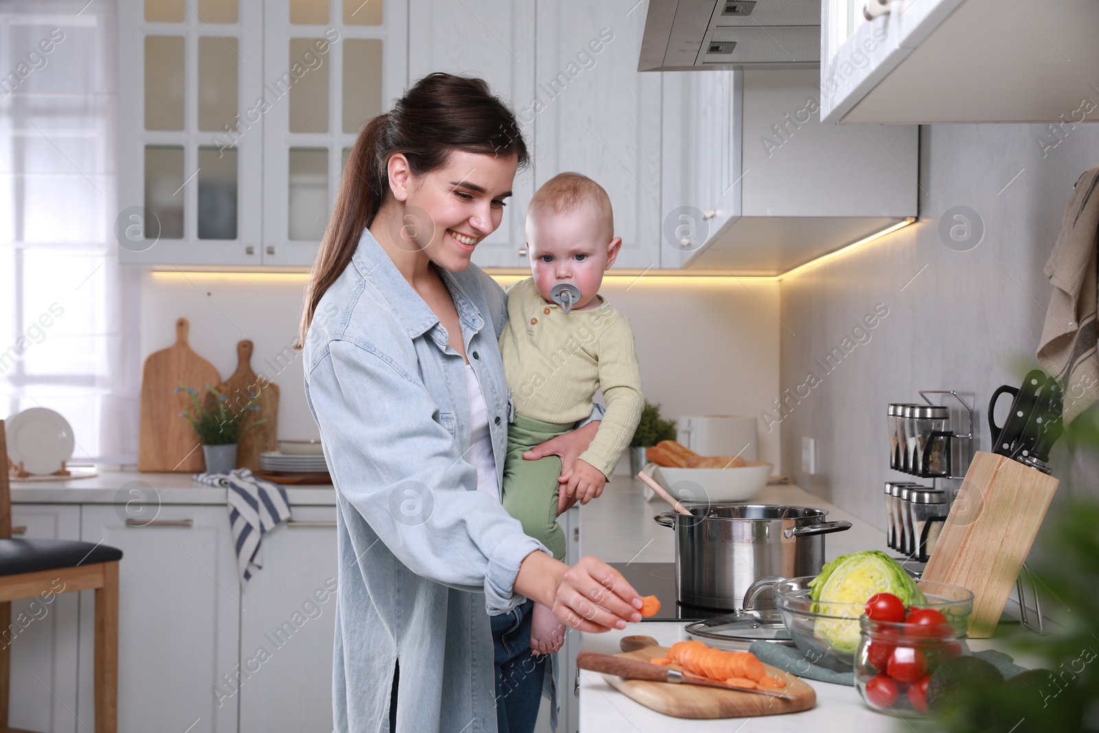 Photo of Happy young woman and her cute little baby cooking together in kitchen