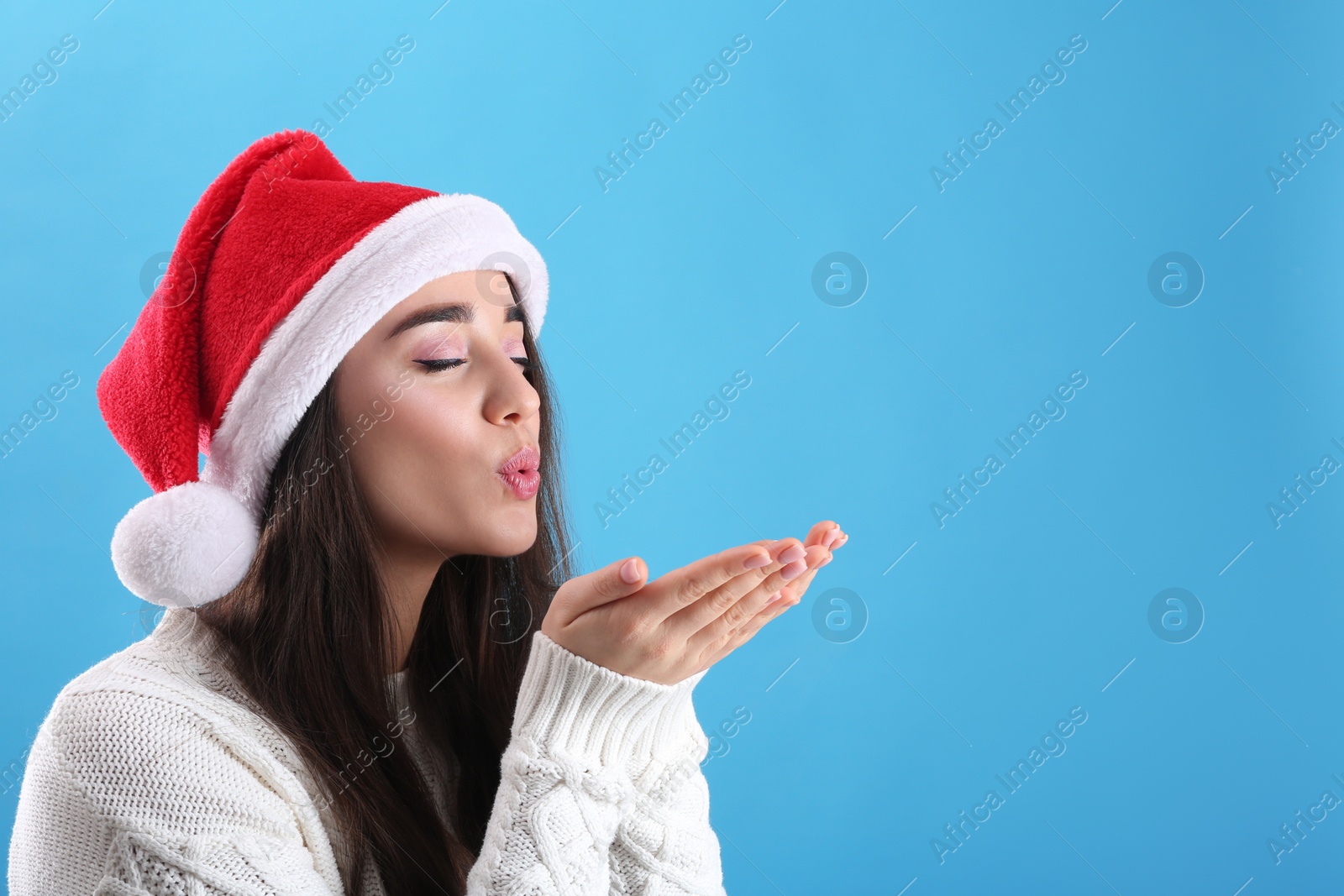 Photo of Beautiful woman wearing Santa Claus hat on light blue background. Space for text