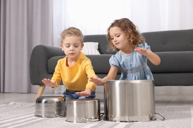 Photo of Little children pretending to play drums on pots at home