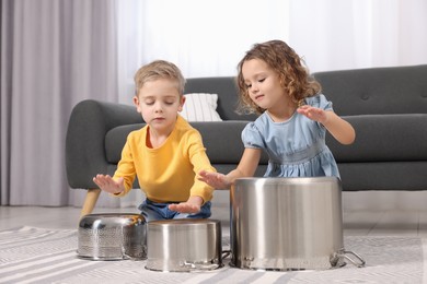 Little children pretending to play drums on pots at home