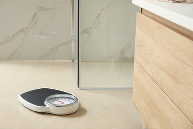 Photo of Scales on floor in bathroom. Overweight problem