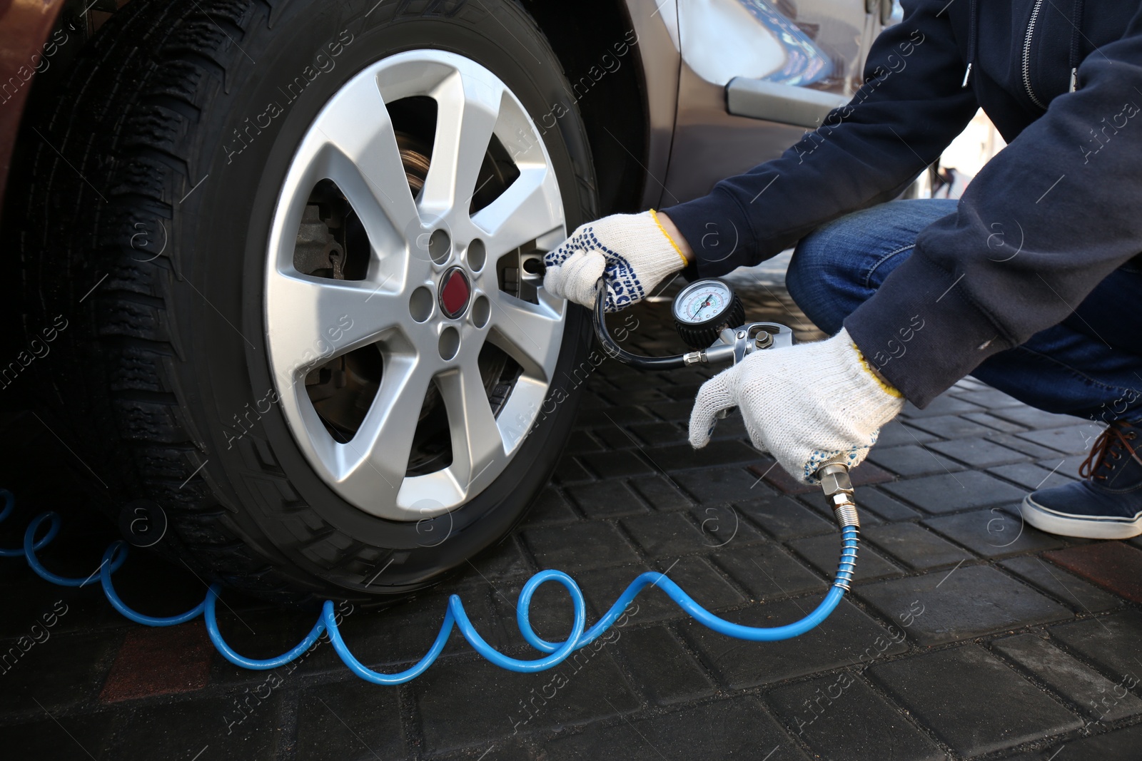 Photo of Mechanic checking tire air pressure at car service, closeup