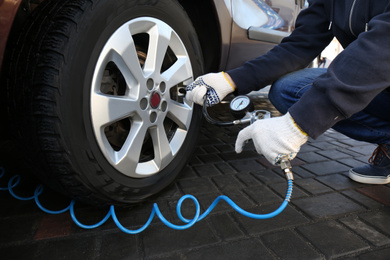 Photo of Mechanic checking tire air pressure at car service, closeup