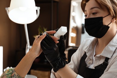 Photo of Professional manicurist working with client in salon, closeup. Beauty services during Coronavirus quarantine
