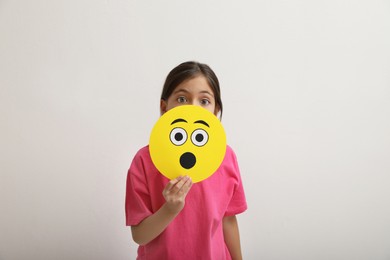 Photo of Little girl covering face with shocked emoji on white background