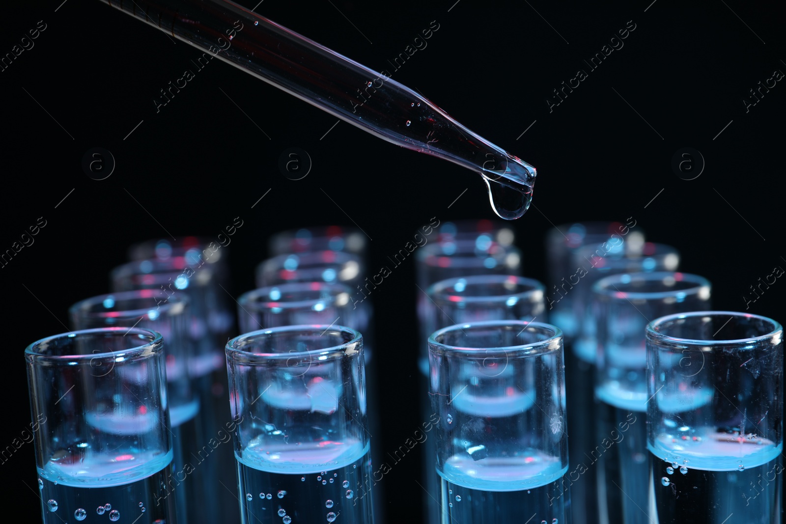 Photo of Dripping reagent into test tube on black background, closeup. Laboratory analysis