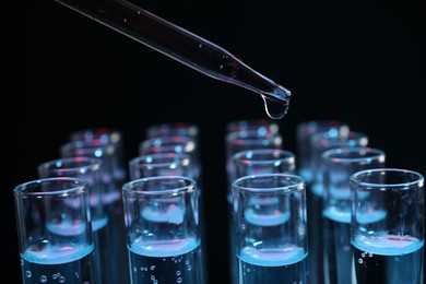 Photo of Dripping reagent into test tube on black background, closeup. Laboratory analysis