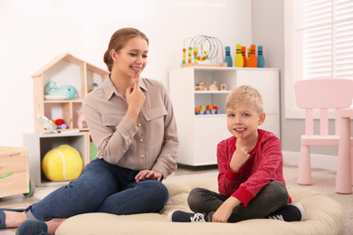 Speech therapist working with little boy in office