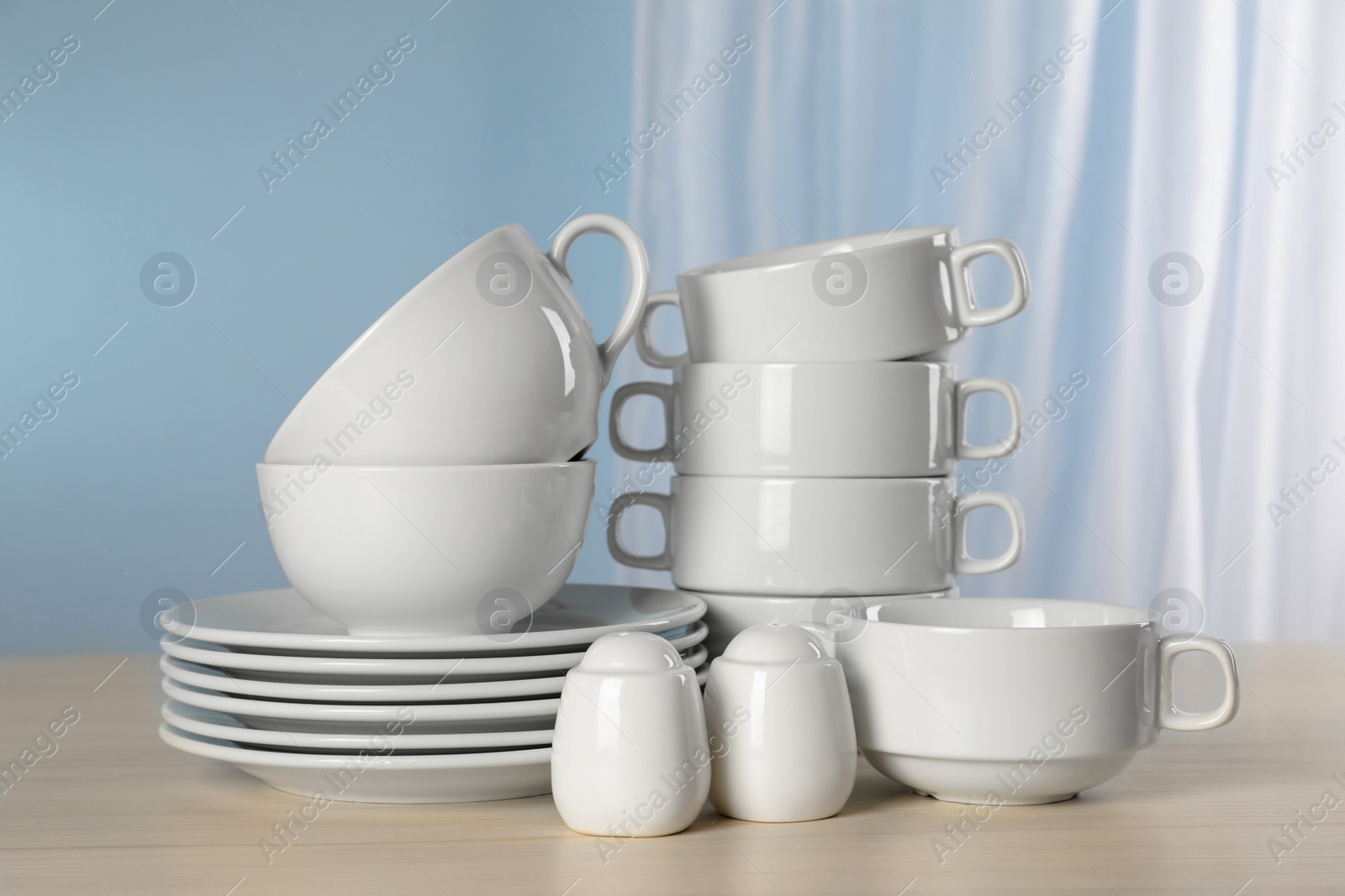 Photo of Set of clean dishware on light grey table