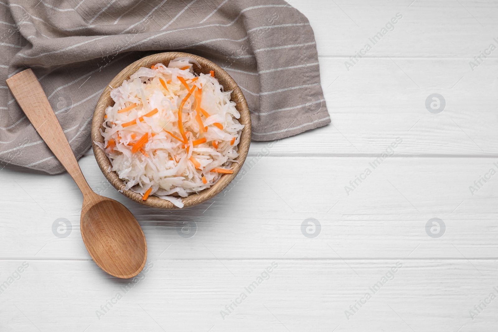 Photo of Bowl of tasty sauerkraut on white wooden table, flat lay. Space for text