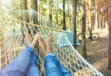 Photo of Couple resting in hammock outdoors on summer day, closeup of legs