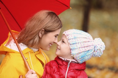 Photo of Mother and daughter with umbrella in autumn park on rainy day