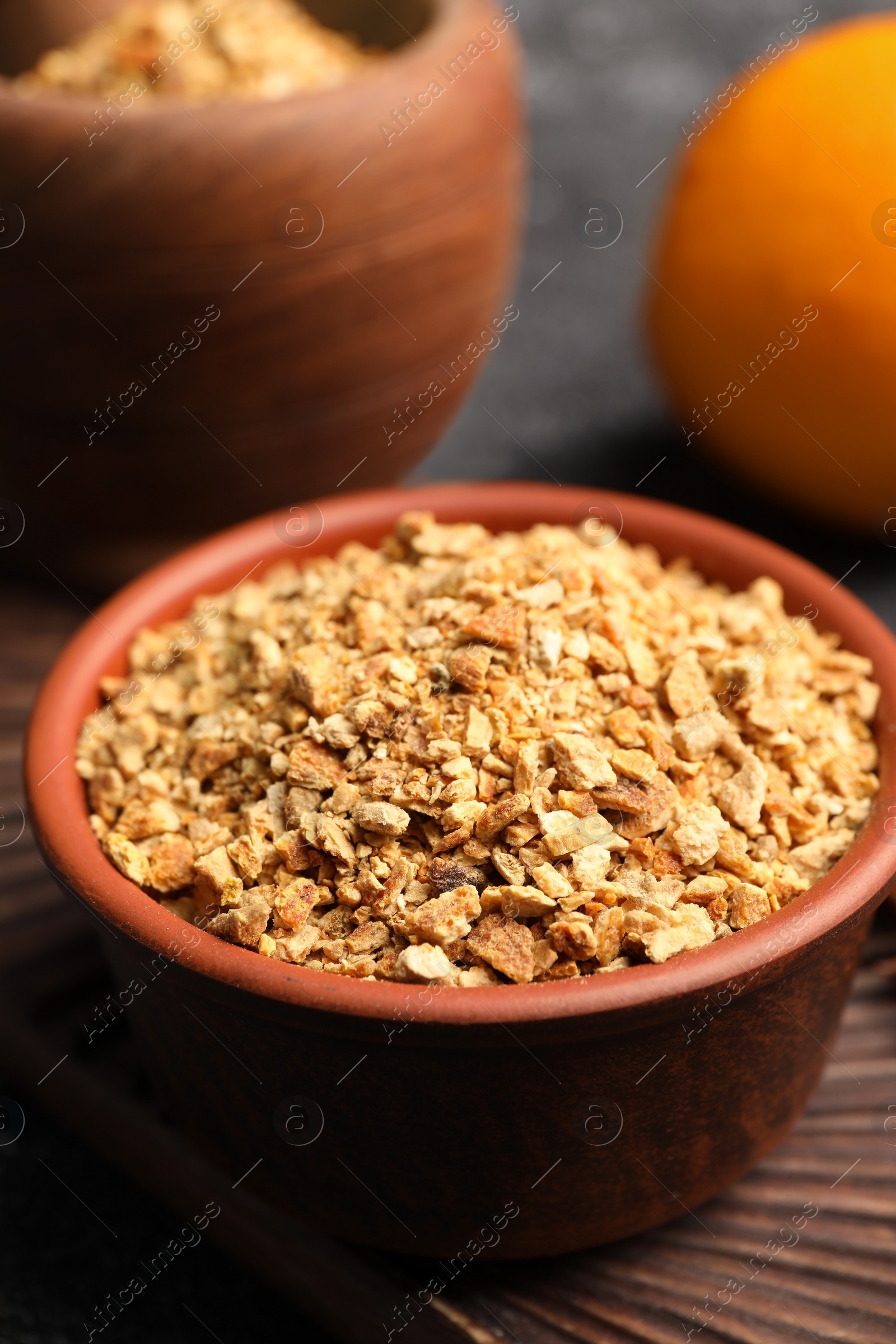 Photo of Bowl of dried orange zest seasoning, fresh fruit and anise on grey table