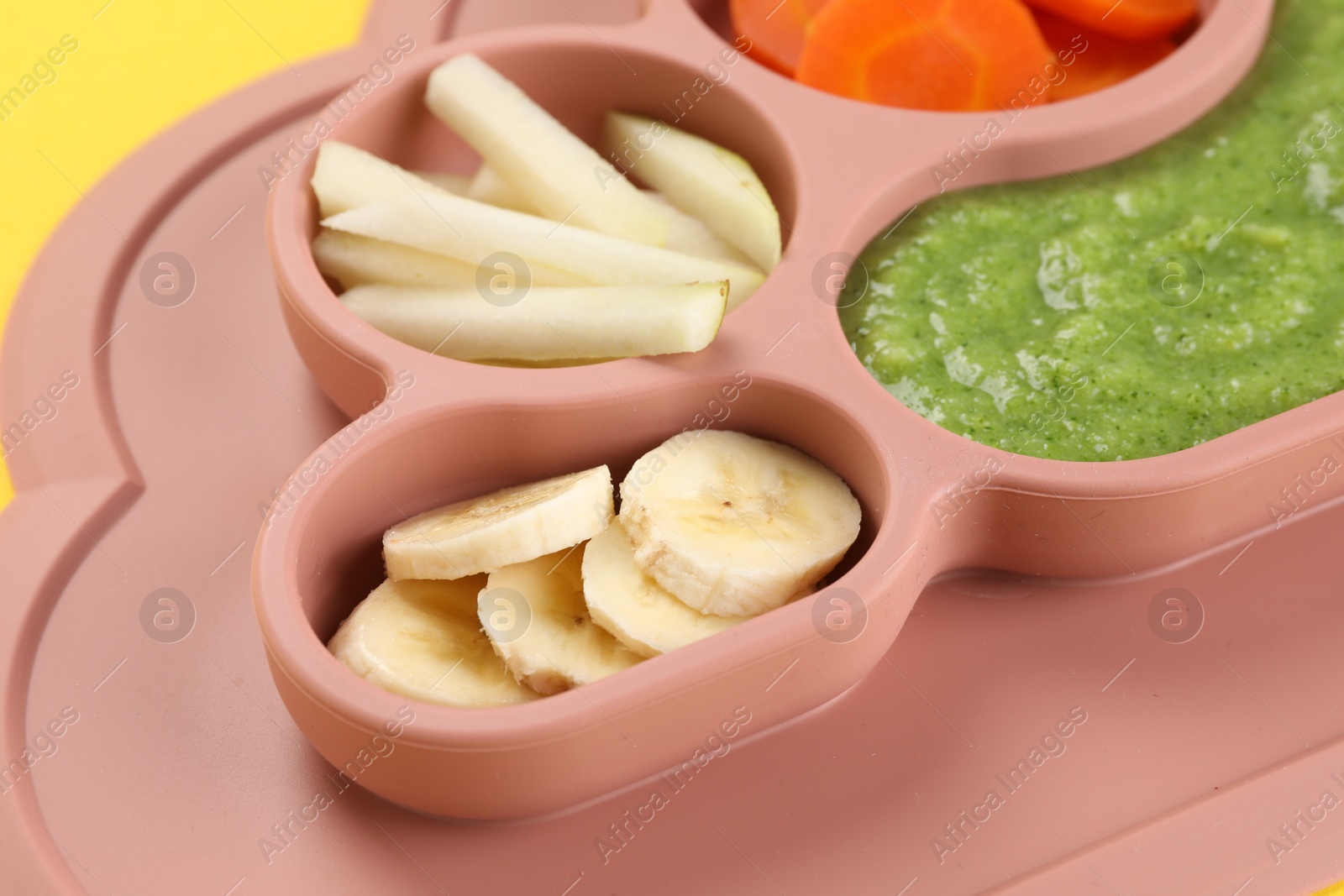 Photo of Healthy baby food. Section plate with delicious broccoli puree, vegetables and fruit on yellow background, closeup