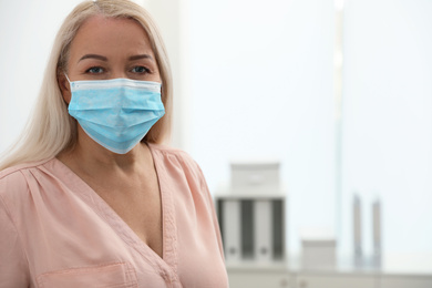 Photo of Mature woman wearing medical mask indoors, space for text. Dangerous virus