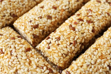 Photo of Tasty sesame seed bars as background, closeup