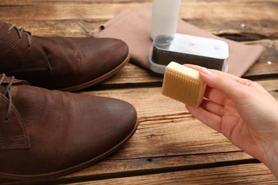 Photo of Woman taking care of stylish shoe at wooden table, closeup