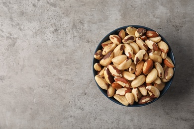 Photo of Bowl with tasty Brazil nuts and space for text on grey background, top view