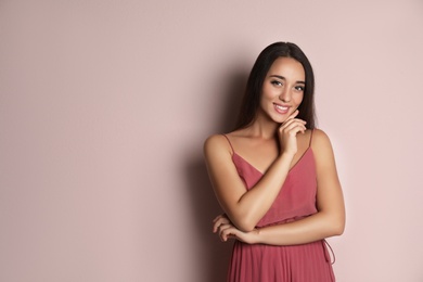 Young woman wearing stylish dress on pale pink background. Space for text