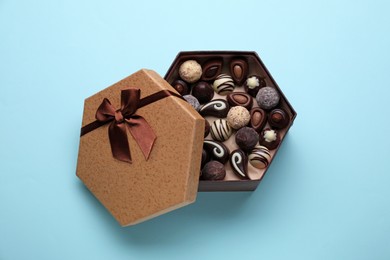 Box of delicious chocolate candies on light blue background, top view