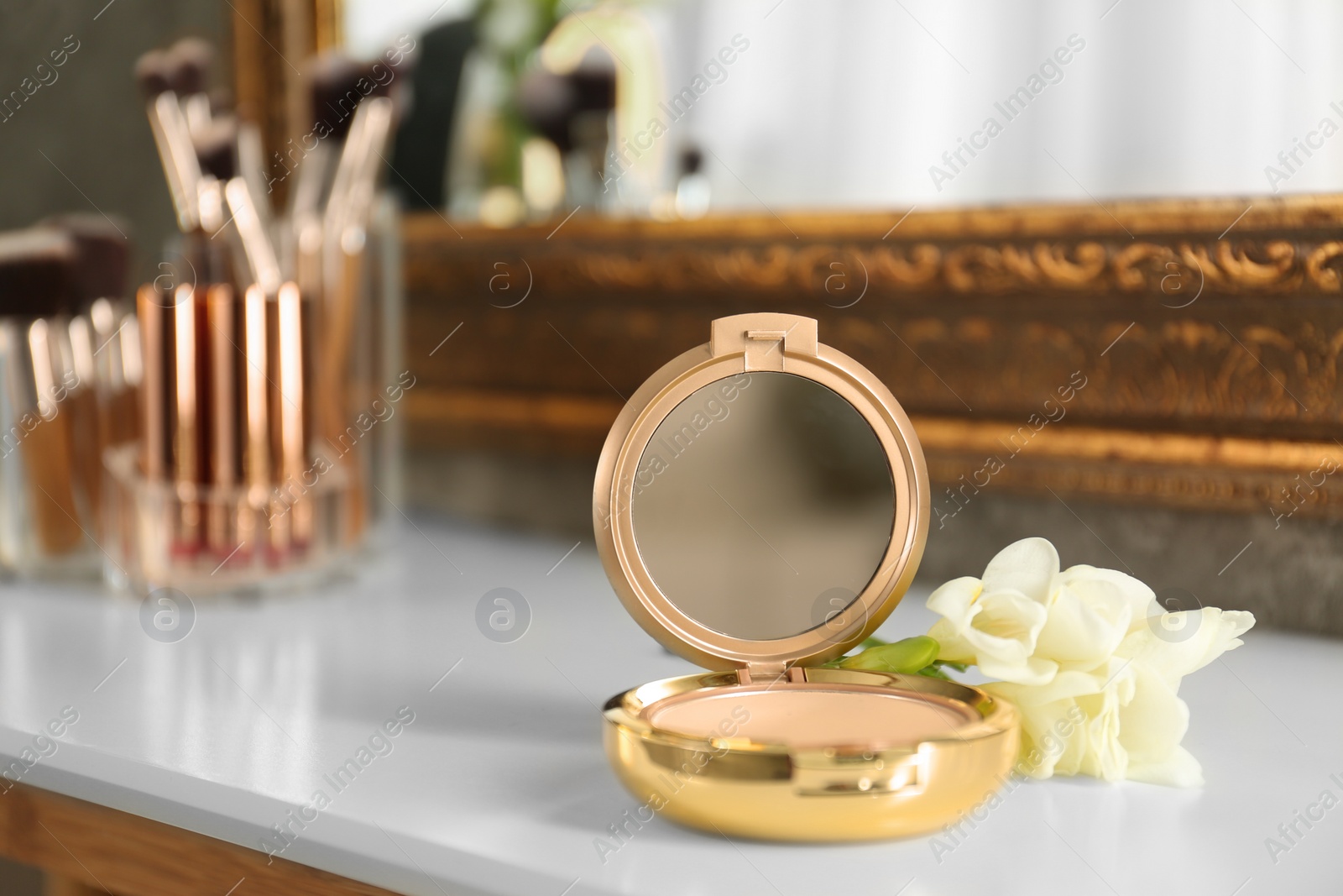 Photo of Luxury compact powder and flowers on dressing table, space for text. Interior element