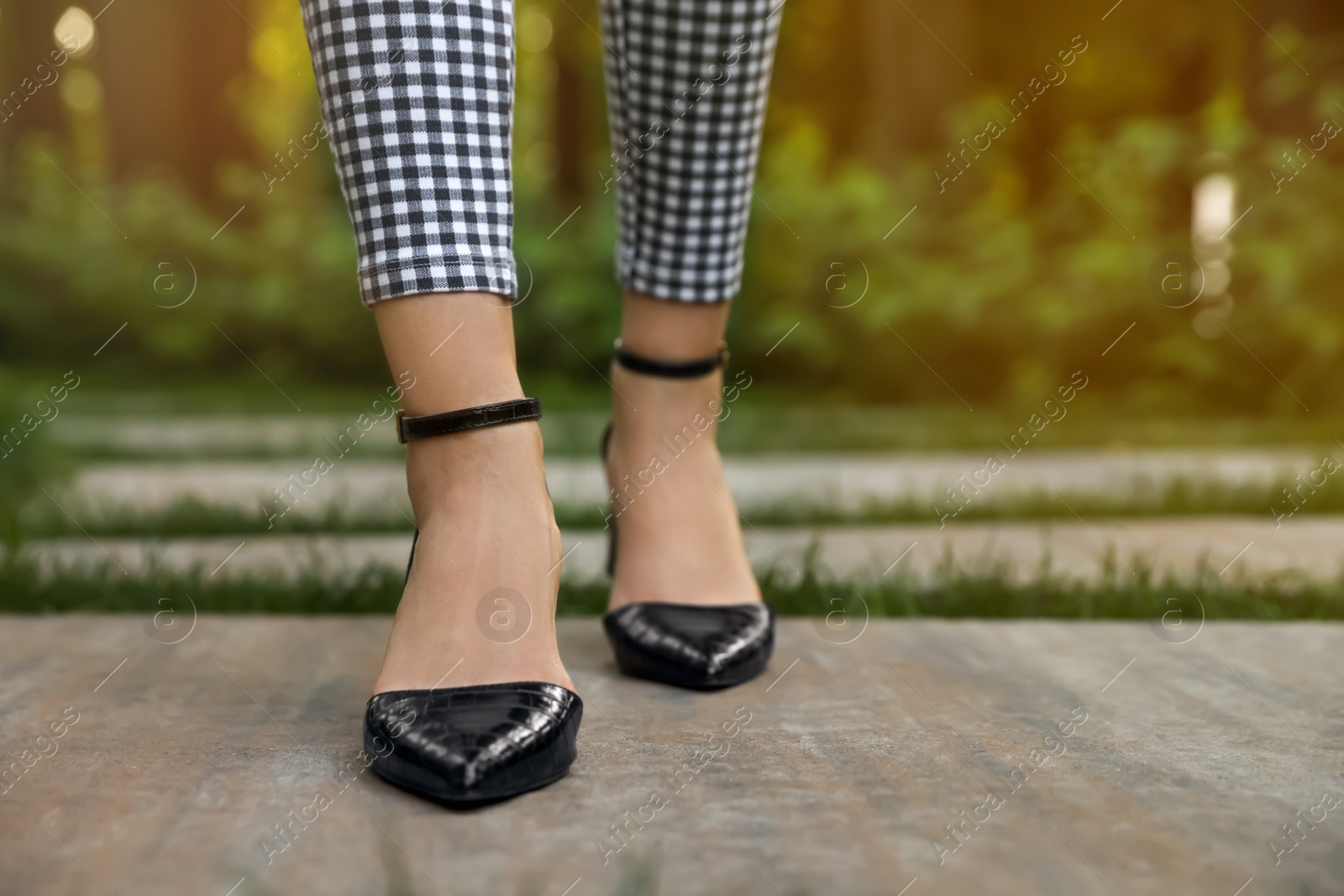 Photo of Woman in stylish black shoes walking at park, closeup