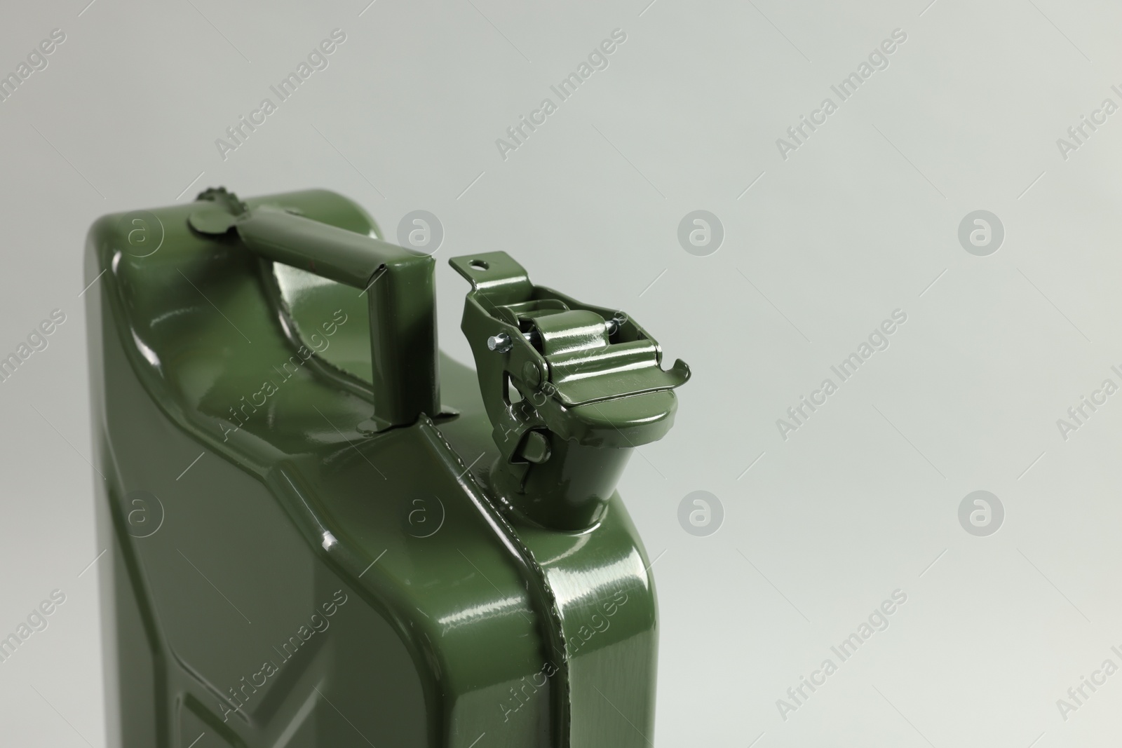 Photo of Green metal canister on light grey background, closeup. Space for text
