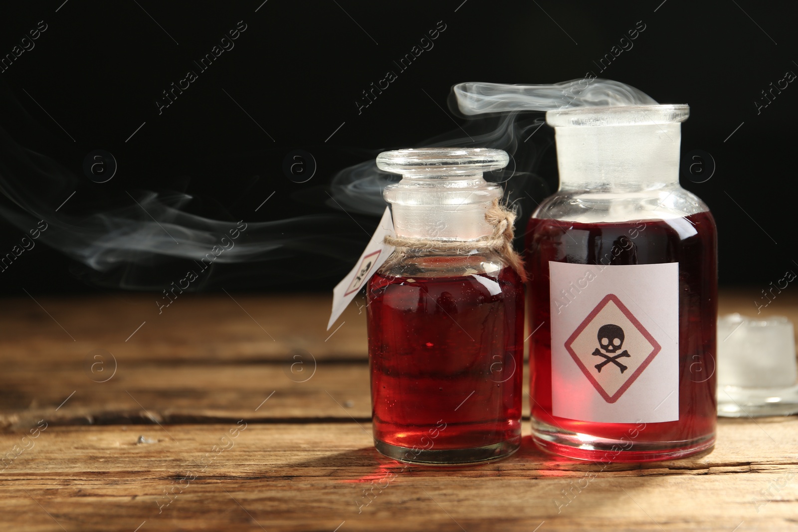 Photo of Glass bottles of poison with warning signs on wooden table. Space for text