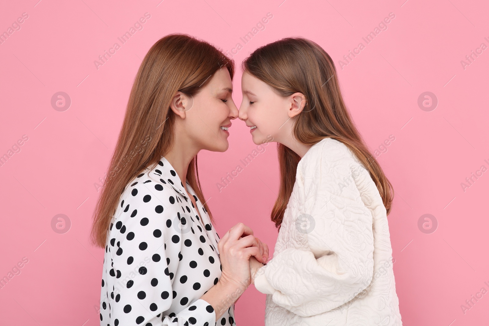 Photo of Portrait of happy mother and her cute daughter on pink background