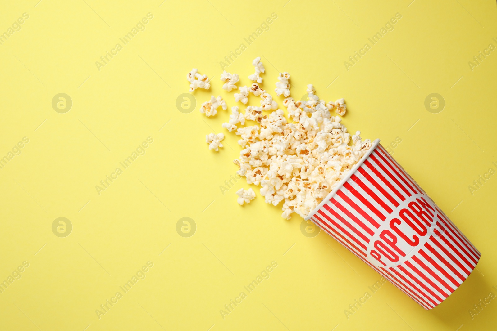 Photo of Delicious popcorn on yellow background, top view. Space for text