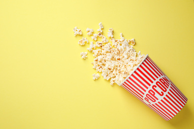 Photo of Delicious popcorn on yellow background, top view. Space for text