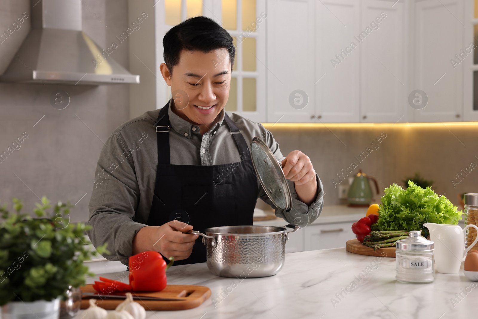 Photo of Cooking process. Man with pot at countertop in kitchen