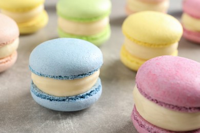 Many delicious colorful macarons on grey table, closeup